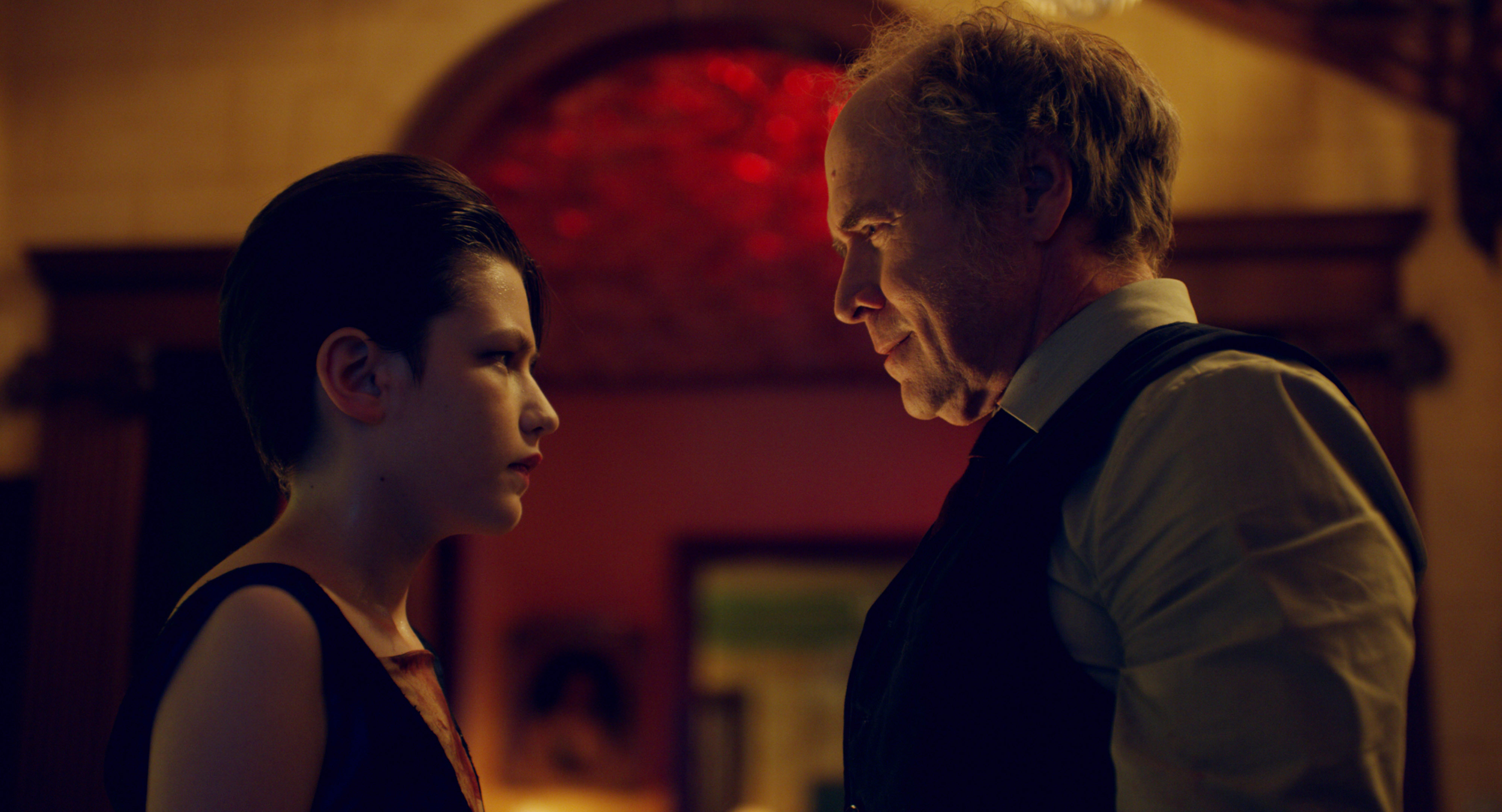 Jacob and Dr. Sherman face each other in a red-lit room.